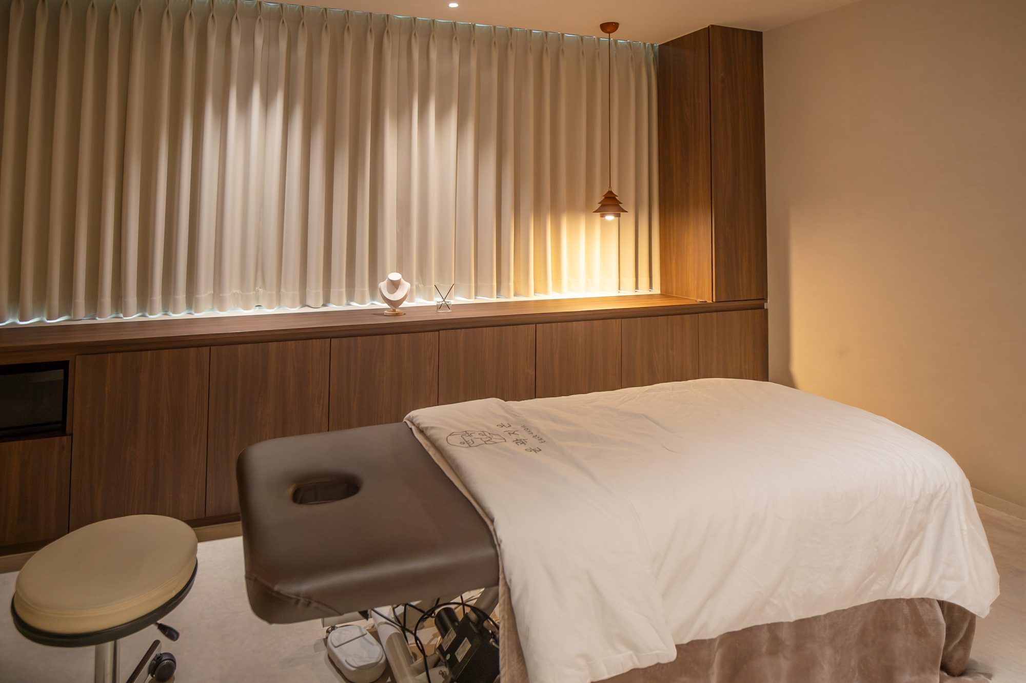 Treatment bed and curtained wall in a private room at Face Jion
